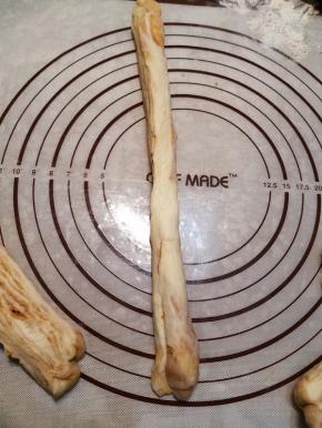 一只手拉着一份面条一端，另一只手按压切面，让面条变扁变长。