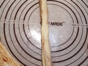 一只手拉着一份面条一端，另一只手按压切面，让面条变扁变长。