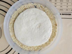 熟白芝麻平铺在盘子里，拿起面团，将刷了蜂蜜水的一面在芝麻上压一下，使面团蘸满芝麻。