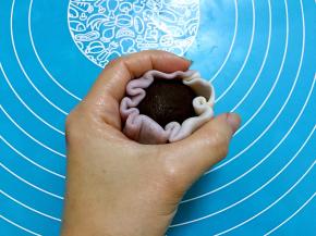 放上豆沙蛋黄，包好后利用虎口慢慢收起