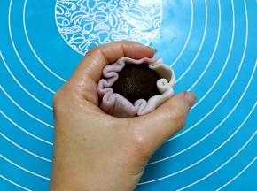 放上豆沙蛋黄，包好后利用虎口慢慢收起