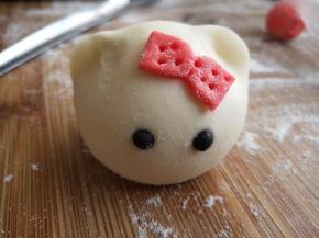 取少许白色面团加一点点黑可可粉揉匀搓圆做眼睛，抹少许水固定