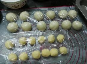 将面团分成12等份，揉圆静置10分钟；将椰蓉馅分成12等份