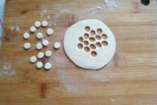 面团静置期间，我们来做小鸟的眼睛和嘴巴：白色小面团擀开，用小号圆形裱花嘴刻出白色小圆形；