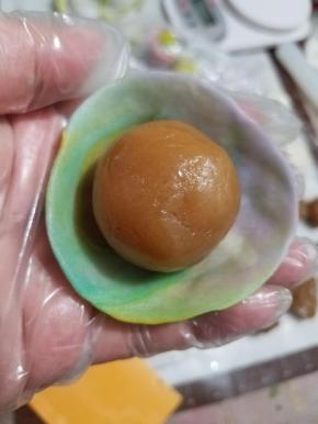 摁扁，然后擀成中间稍厚，两边薄的皮，再把皮翻过来，放入刚才准备好的馅料。