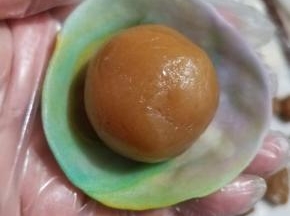 摁扁，然后擀成中间稍厚，两边薄的皮，再把皮翻过来，放入刚才准备好的馅料。