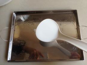 勺一勺调好的肠粉浆入肠粉盘里，我一般是一勺再加一点，用的是电饭锅配送的塑料汤勺。（每次倒入肠粉浆前一定要将粉浆搅拌一下再勺）。