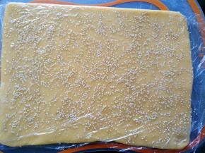 把剪开的保鲜膜盖上，用手轻松压一下，使芝麻粘更紧