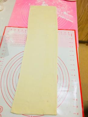 将包裹好黄油片的面，擀成长方向。从中间往两端擀，不要反复擀