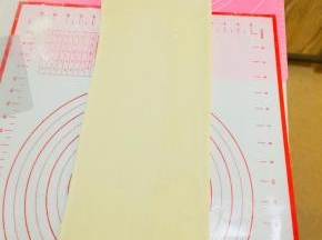 将包裹好黄油片的面，擀成长方向。从中间往两端擀，不要反复擀