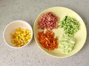 把胡萝卜和黄瓜洗净去皮，切碎，西兰花洗净切碎，火腿肠切碎，玉米煮熟，剥粒。