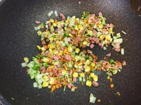 接着把火腿碎和玉米粒放入锅中翻炒。