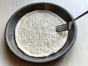 用擀面杖擀圆，放入烤盘中，再用叉子叉满洞洞，如图。