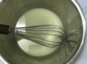 将玉米油和水倒入大碗中，用手动打蛋器搅拌均匀。