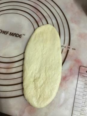 将面团擀成长舌状卷起。