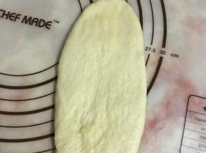 将面团擀成长舌状卷起。