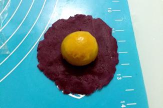 把紫薯馅按扁放入鸭蛋黄