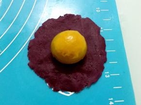 把紫薯馅按扁放入鸭蛋黄
