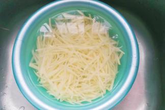 切好的土豆丝过清水多冲洗几次，然后浸泡一小会儿再捞起沥干水；
