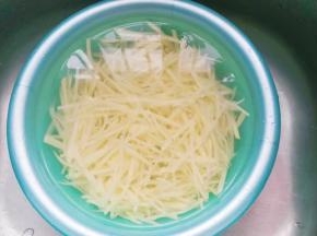 切好的土豆丝过清水多冲洗几次，然后浸泡一小会儿再捞起沥干水；
