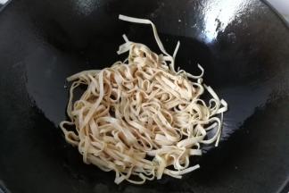 锅中入适量油，先下豆腐皮炒一下；