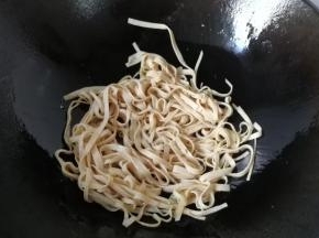 锅中入适量油，先下豆腐皮炒一下；