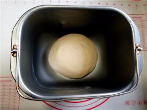 倒入酵母牛奶液启动一个和面程序和成面团，加入黄油再启动一个和面程序，揉到扩展阶段。