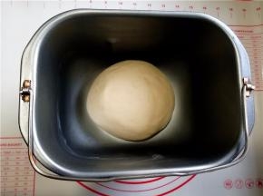 倒入酵母牛奶液启动一个和面程序和成面团，加入黄油再启动一个和面程序，揉到扩展阶段。