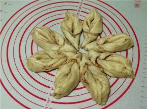 将三角的头部拉起向内弯曲穿过割口缝隙并拉直，.将三角的尾部两边捏合在一起。