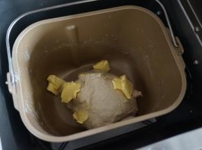 面团静置5分钟后加入切成小块的黄油