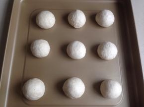 发酵好的面团取出，用手掌压出面团里的气体，将面团分成9等份，滚圆，放在烤箱自带的不粘烤盘上