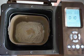 在面粉顶端加入酵母，将面包桶放入到东菱1352AE-3C面包机里，选择和面10分钟