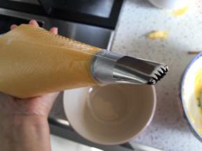 用扁嘴的裱花嘴套在裱花袋内，把泡芙面糊刮入裱花袋中