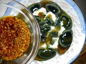 切好的豆腐和皮蛋放入盘中，倒上姜蒜汁。