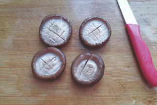 香菇捞起，用手轻轻挤压多余水份，然后用小刀打上十字花刀；