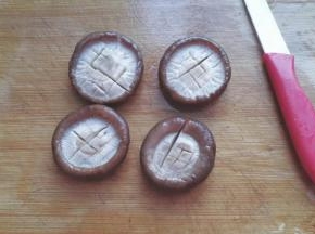 香菇捞起，用手轻轻挤压多余水份，然后用小刀打上十字花刀；