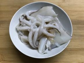 墨鱼买回来后剥去外面的黑衣，洗净。