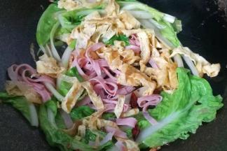 再放入火腿丝和鸡蛋皮，加少许盐翻炒均匀；