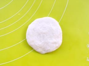 揭开保鲜膜，将面团翻个面，因为擀的一面比较光滑，我们用不光滑的一面来包裹椰蓉馅