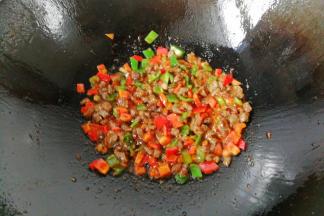 接着倒入青红椒碎丁炒一下，再调入少许生抽、胡椒与鸡精炒均后盛起来；