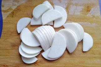 将萝卜从中间切开，再切成稍微厚点的萝卜片；