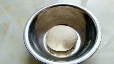 面粉中加入发酵粉，温水适量揉成软硬适中的面团，盖上湿布进行发酵。