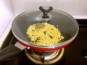 炒锅中火做热，倒入玉米粒平铺在底部，盖上锅盖。转小火，不时的晃一晃。