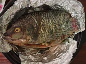 剩下的锡纸折好放在烤架上面，贴合锅体并把高出锅的锡纸往外翻压，把刷了油的罗飞鱼放入黑乐砂锅里