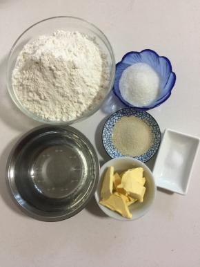 准备好主面团所需的材料:
面包粉500克，酵母6克，凉水320克，白糖60克，盐2克，黄油50克！