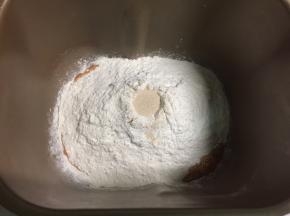在胡萝卜泥上加入200克面粉，面粉顶部掏一个洞，加入3克酵母。