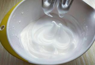 电动打蛋器高速打发，打至湿性发泡时加入最后的三分之一糖粉，，继续打发至蛋白出现细腻的纹路，将电动打蛋器调低速打发一会儿，感觉有些阻力时，就可以停止打发，以免消泡，提起打蛋器有微微的弯勾就可以，如图