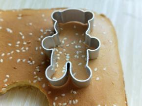 蛋糕烤好后，戴上隔热手套迅速取出烤盘，垂直摔一下，震出热气，趁热撕下油纸，翻面朝上，撕掉油纸后马上将蛋糕翻面，正面朝上，不然水蒸气加热气会导致蛋糕皮被粘掉。 之后用模具压出小熊的图案即可，没有模具的可以用碗压圆形，或者直接用刀切片都可以。