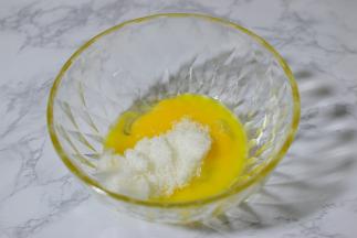 蛋黄和蛋清分别装在两个容器中。蛋黄中加入一半的白糖，搅拌均匀。