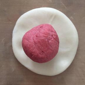 将（之前分好了四份的油皮）每份油皮平均分成3份，一共是12份揉圆。

接下来，取一份油皮，按扁，包入一份油酥。